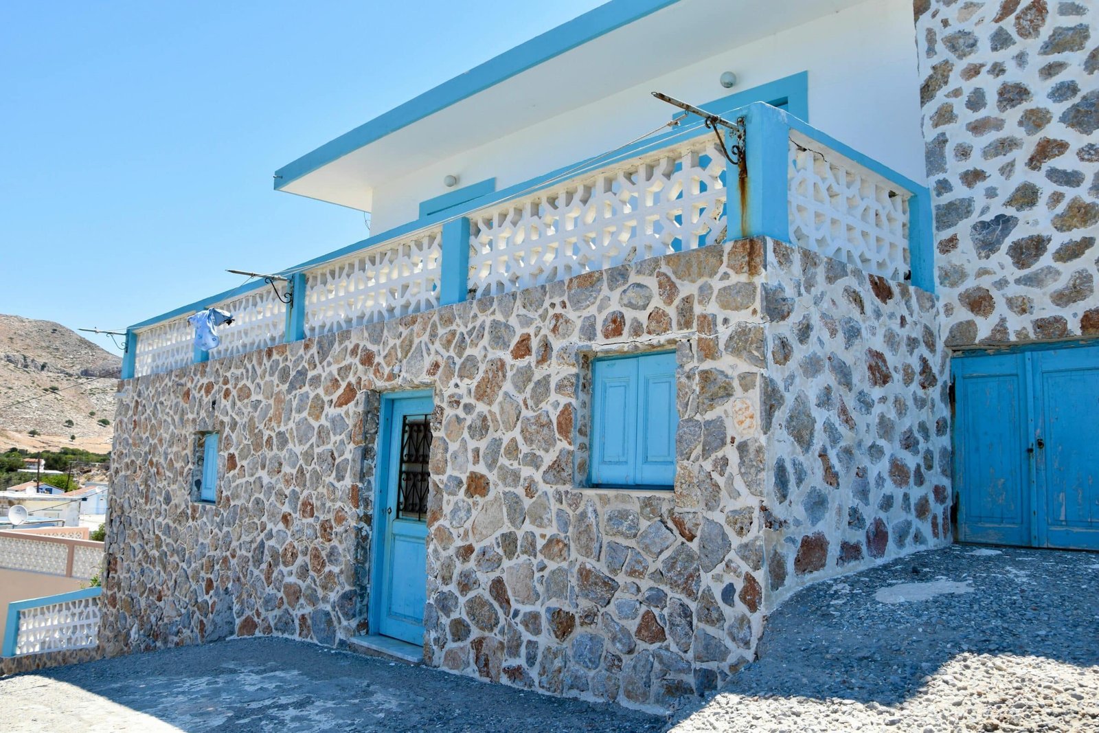 Traditional stone house with blue trim and balcony in a sunny setting